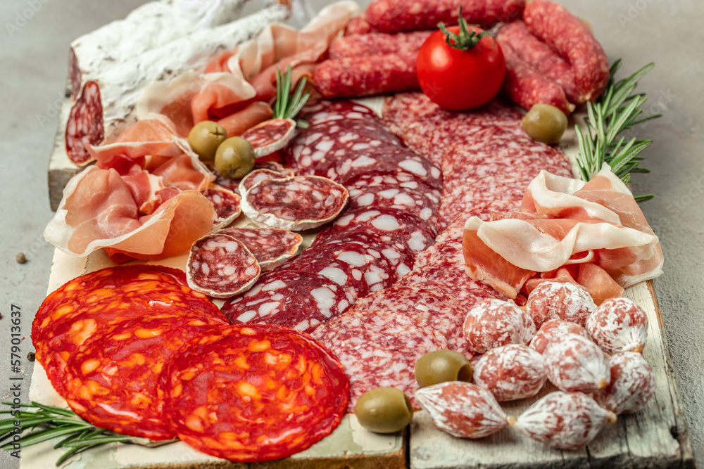Antipasto platter. Cold cuts prosciutto, bacon, salami and sausages on a wooden board. catering, banner, menu, recipe. top view