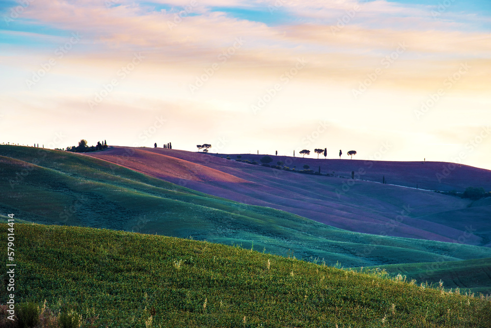 Scenic landscape with colored hills against clouds in Tuscany, Italy at sunrise. Charming place