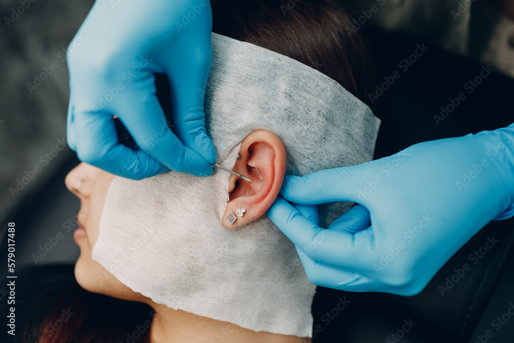 Young woman doing piercing at beauty studio salon