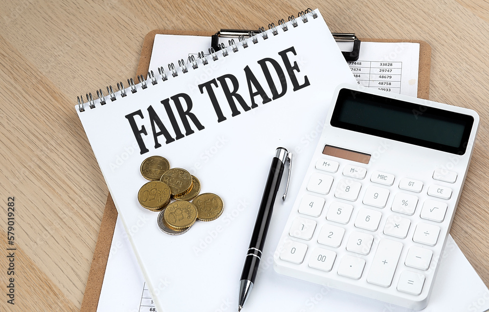 FAIR TRADE text on a notebook with chart and calculator and coins, business concept FAIR TRADE text on a notebook with chart and calculator and coins, business concept