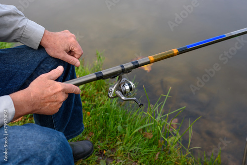 Elderly angler holds fishing rod in his hand. Leisure