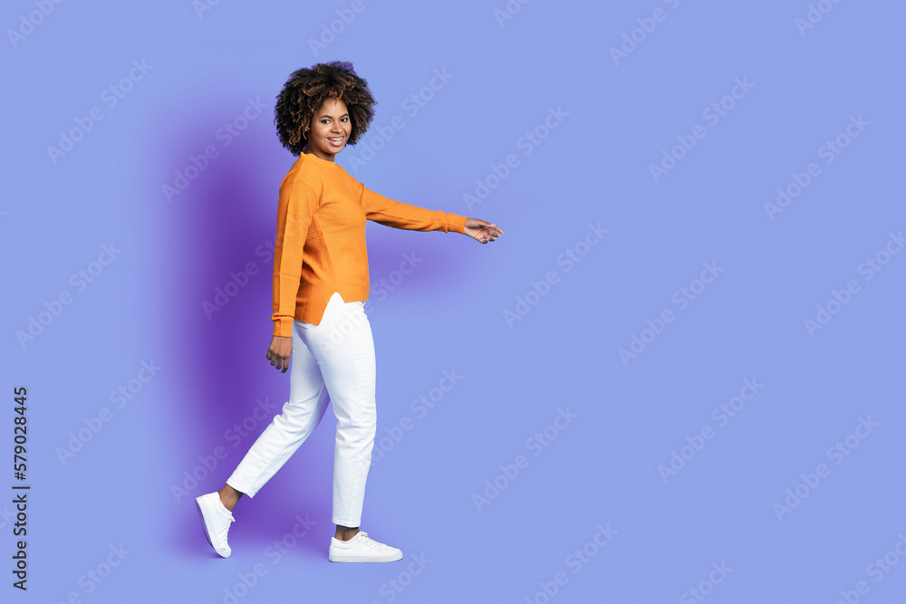 Cheerful stylish curly black woman walking towards copy space Cheerful stylish curly black woman walking towards copy space