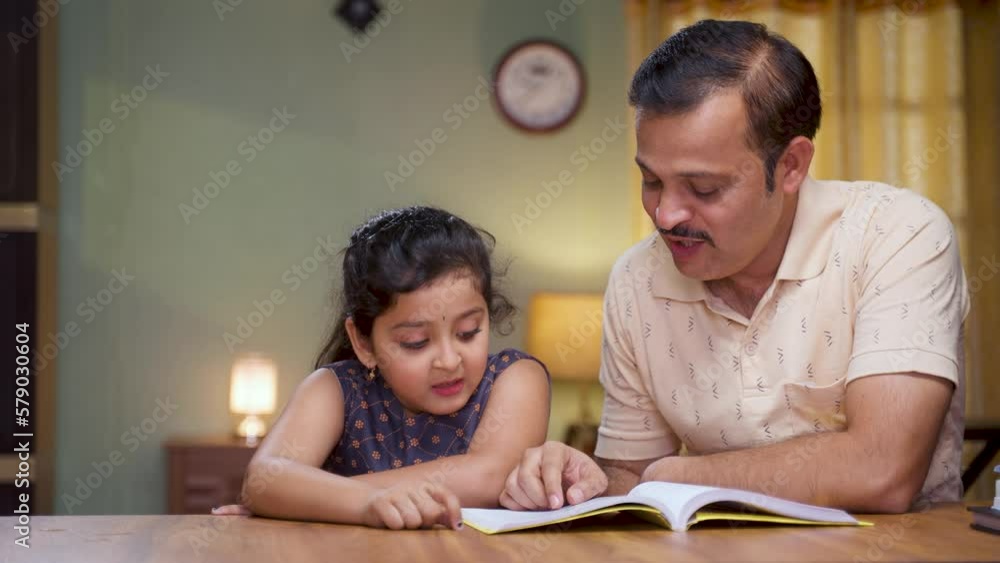 Father helping his daughter for reading book at home during evening - concept of education, caring family and responsibility Father helping his daughter for reading book at home during evening - concept of education, caring family and responsibility