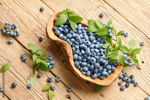 Fresh blueberries in wooden dish on planks background