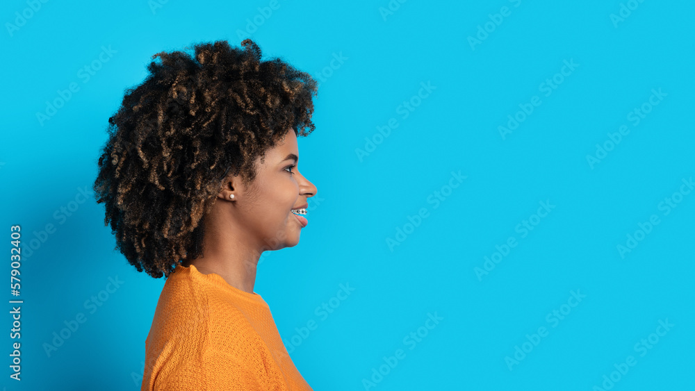 Profile portrait of young black woman posing on blue Profile portrait of young black woman posing on blue
