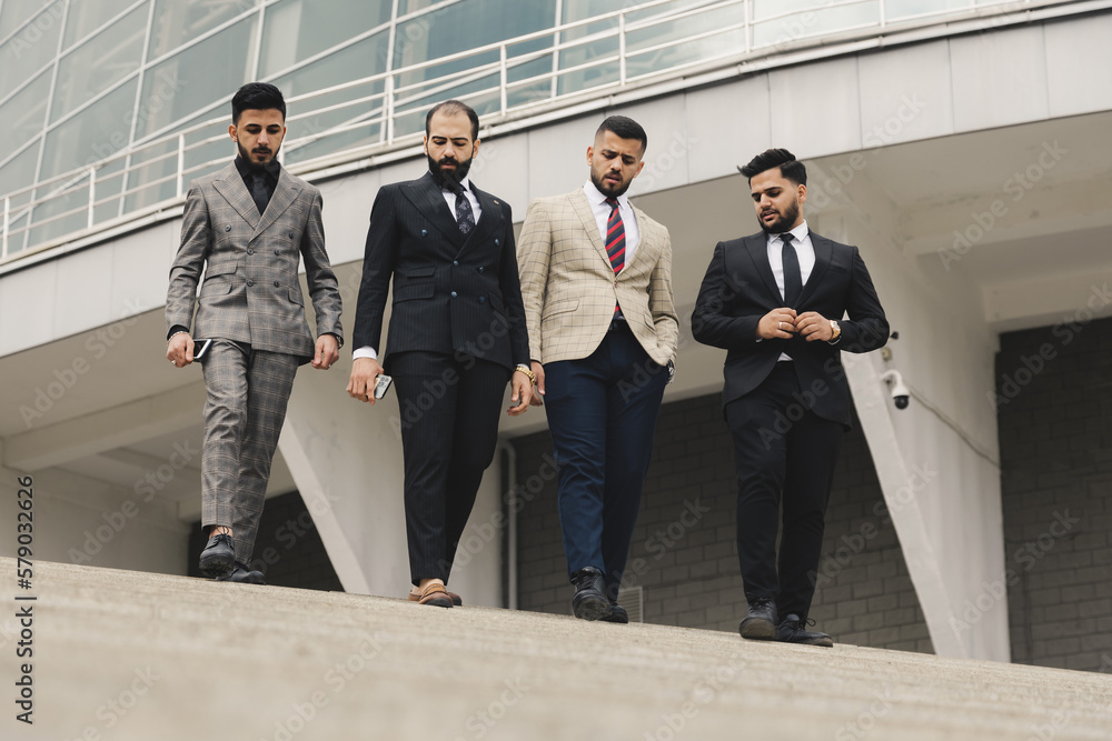 Business people outdoor meeting. A company of male businessmen in suits descend down the street stairs. Working break. Teamwork and brainstorming. Successful teamwork. Business people outdoor meeting. A company of male businessmen in suits descend down the street stairs. Working break. Teamwork and brainstorming. Successful teamwork.