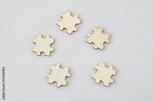 Five wooden puzzles on beige background, copy space
