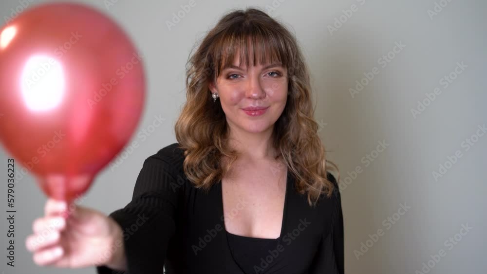 Young Woman Handing a Balloon to the Camera Young Woman Handing a Balloon to the Camera