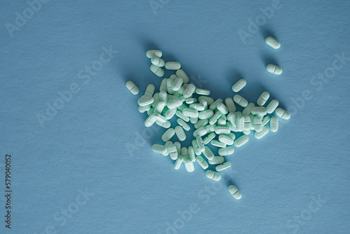 Pharmaceutical nutraceutical medicine green tablets spilled on blue background photo