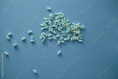 Pharmaceutical nutraceutical medicine green tablets spilled on blue background