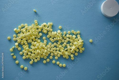 Pharmaceutical nutraceutical medicine yellow tablets spilled on blue background in sun shape