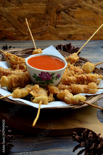 Selective focus Cilor Tusuk or Aci Telur Gulung is a typical Indonesian snack. Served on wooden table photo