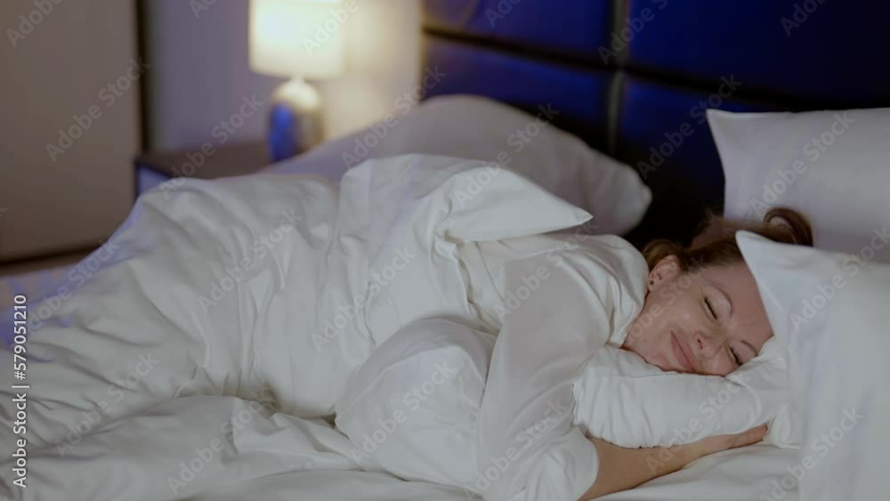Portrait of an adult happy beautiful woman lying in bed in the early morning after waking up. Cute beautiful girl looks happy in the bedroom on a pillow. Portrait of an adult happy beautiful woman lying in bed in the early morning after waking up. Cute beautiful girl looks happy in the bedroom on a pillow.