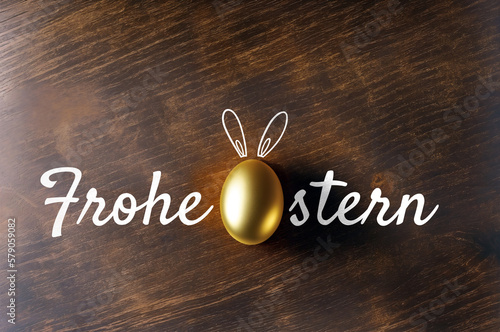 Frohe Ostern! Goldenes Osterei auf einem Holztisch mit einem Schriftzug. Platz für Text. 