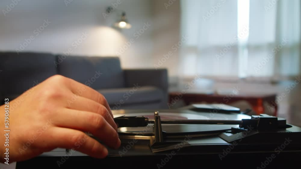 Man turns on a vinyl record on an old player and sits down on the sofa to work on a laptop or buy something online. Modern man works online and listens to music. Man turns on a vinyl record on an old player and sits down on the sofa to work on a laptop or buy something online. Modern man works online and listens to music.