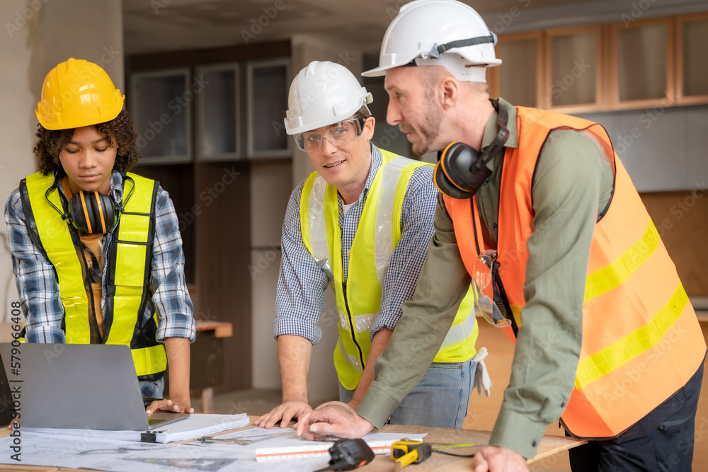 Architect colleagues mixed race working as a team discussing data working and tablet, laptop with on on architectural project at construction site at desk. Architect colleagues mixed race working as a team discussing data working and tablet, laptop with on on architectural project at construction site at desk.