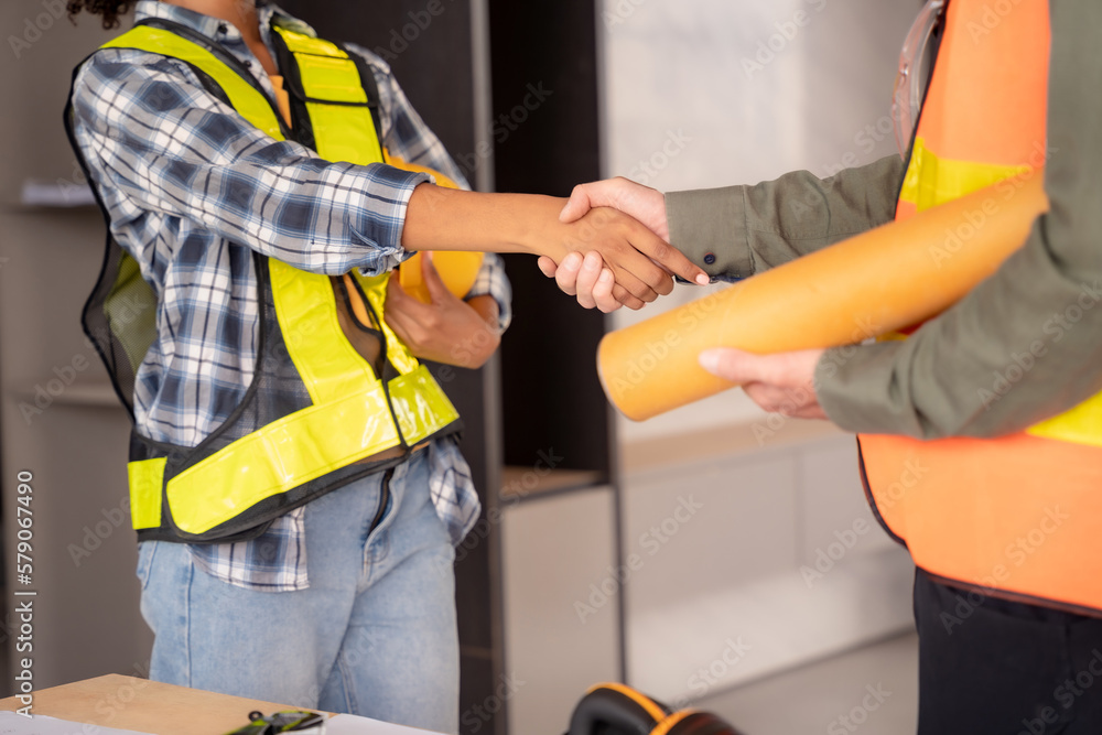 Construction workers, architects and engineers shake hands while working for teamwork and cooperation after completing an agreement in an office facility, successful cooperation concept. Construction workers, architects and engineers shake hands while working for teamwork and cooperation after completing an agreement in an office facility, successful cooperation concept.