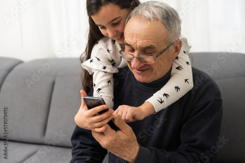 Foto senior grandfather learning to using mobile phone under guidance of pretty young