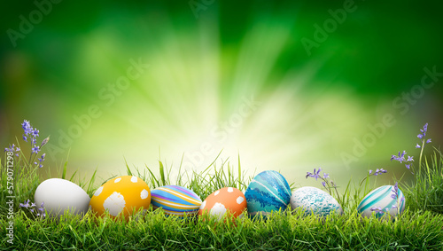 A collection of painted easter eggs celebrating a Happy Easter on a spring day with green grass meadow background with copy space.