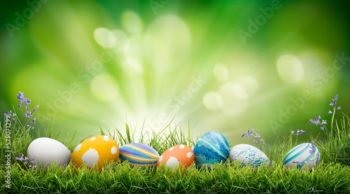 Obraz na płótnie A collection of painted easter eggs celebrating a Happy Easter on a spring day with green grass meadow background with copy space. w salonie
