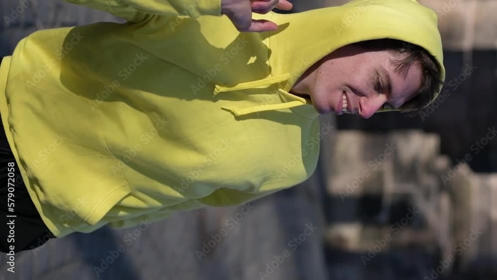 Smiling man in yellow sweatshirt with a headphones listening music outdoors Smiling man in yellow sweatshirt with a headphones listening music outdoors