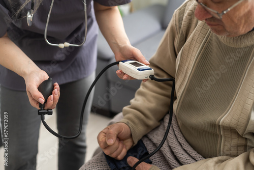 Nurse measure high blood pressure of a sick senior mature male patient in medical clinic closeup. Doctor checking arterial blood pressure of elderly man with hypertension. Healthcare concept
