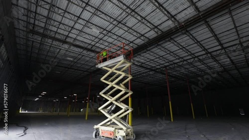 Man operating a scissor lift in a warehouse under construction. photo