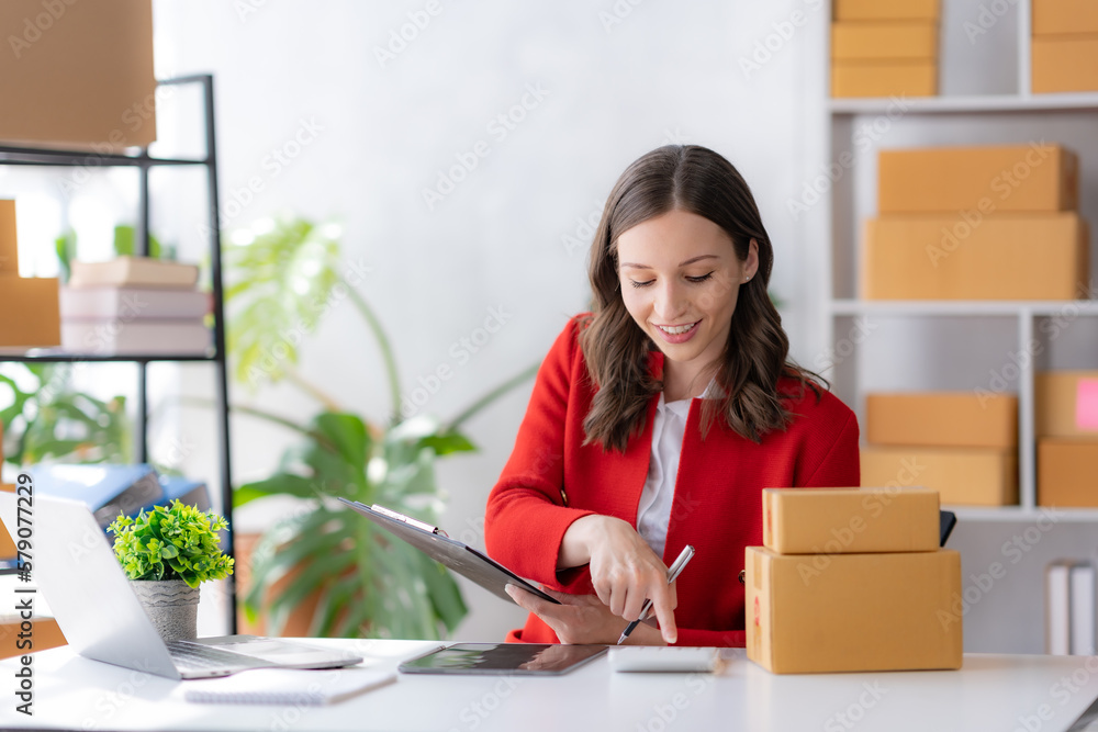 Female ecommerce business owner prepares package box for customer and delivery check balance. SME.