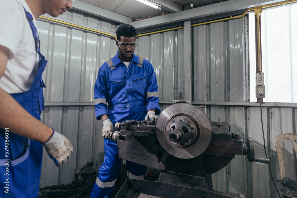 Diversity mechanic worker or metalworker using metal lathe machine operate polishing car disc brake at auto repair garage. Maintenance automotive and inspecting vehicle part concept Diversity mechanic worker or metalworker using metal lathe machine operate polishing car disc brake at auto repair garage. Maintenance automotive and inspecting vehicle part concept