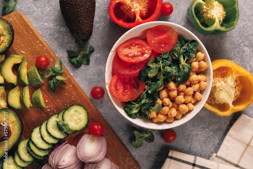 closeup view of healthy veggie poke, fill with chickpeas, arucgula, tomato and several vegetables around