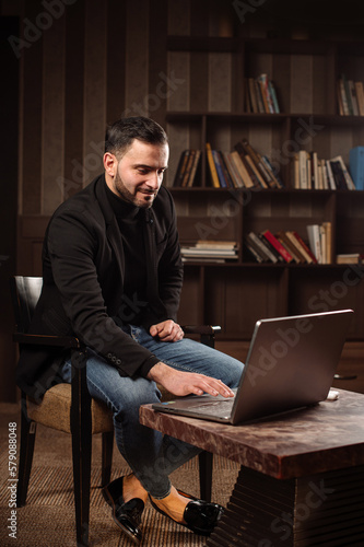 handsome bearded male bussiness man is wirking with a laptop in his home office