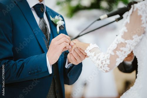 Novio pone anillo a su novia en su boda