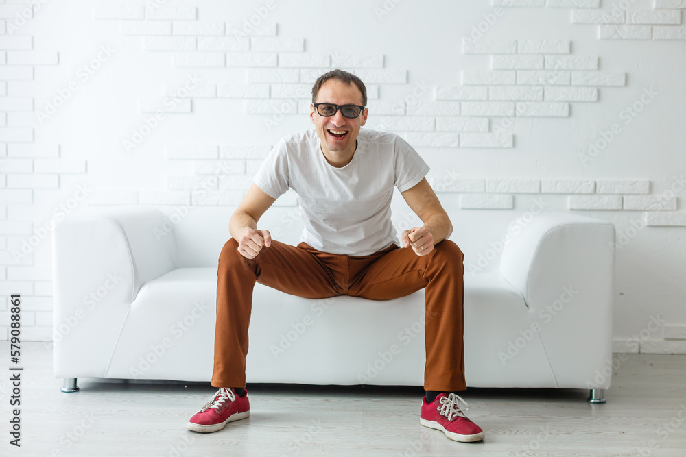 Fototapeta premium Portrait of the young man in white on sofa.