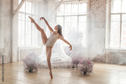 Fotografia professional ballerina in a white gymnastic leotard is dancing in a room