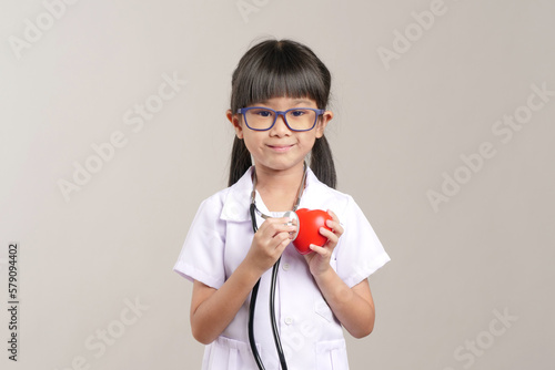Kid doctor holding a stethoscope and checking heart. Kid role playing doctor.
