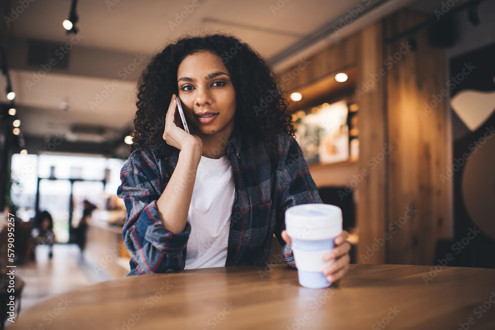 Smiling black woman talking on smartphone in cafe Smiling black woman talking on smartphone in cafe
