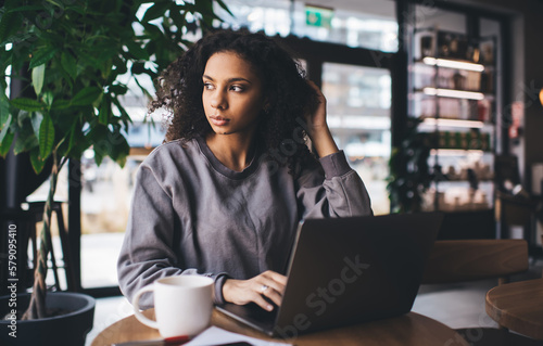 Thoughtful black woman working on laptop in cafe