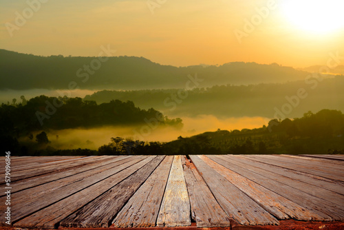 	
An empty wooden terrace with mountain view and mist during sunrise.		
