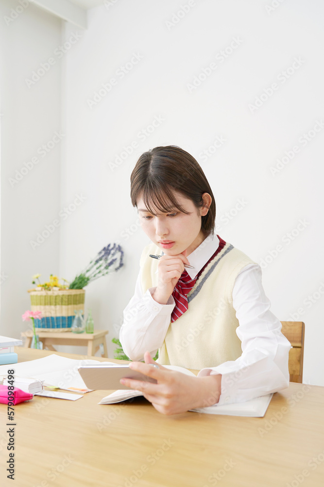 家でスマホの学習アプリを使って勉強する女子高生 家でスマホの学習アプリを使って勉強する女子高生