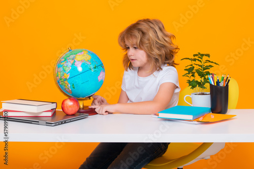 Kid boy from elementary school with book on yellow isolated background. Little student, smart nerd pupil ready to study. Concept of education and learning.