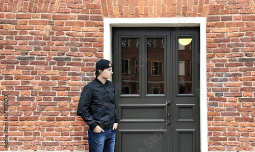 Young man standing near the front door of a brick house