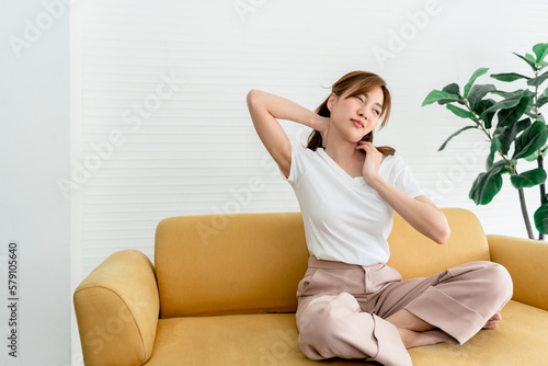Asian woman, attractive and young sitting on a sofa, is currently having a nape injury, to people and health care concept.