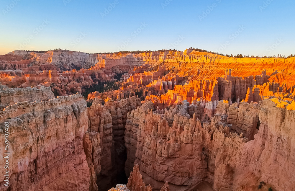 Aerial sunrise view of impressive hoodoo sandstone rock formations in Bryce Canyon National Park, Utah, USA. First morning sun rays touching on natural unique amphitheatre sculpted from red rocks