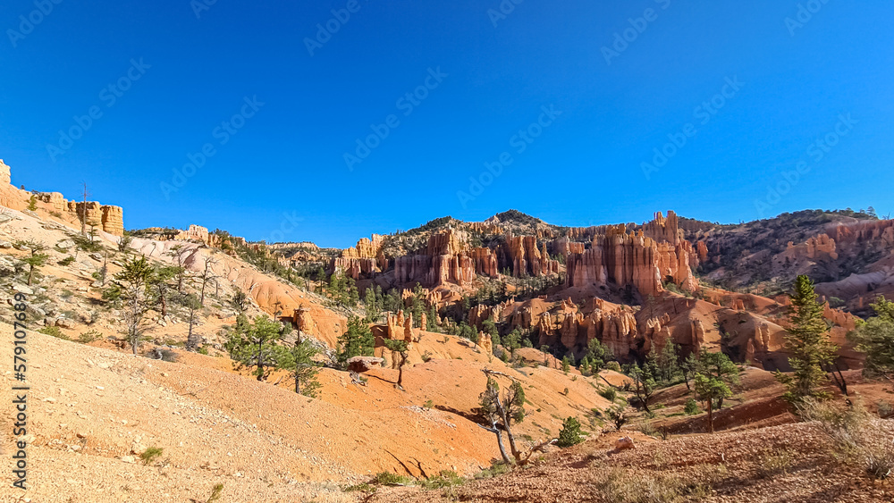 Panoramic Fairyland hiking trail with scenic view on massive hoodoo wall sandstone rock formation in Bryce Canyon National Park, Utah, USA. Pine trees along the way. Unique nature in barren landscape Panoramic Fairyland hiking trail with scenic view on massive hoodoo wall sandstone rock formation in Bryce Canyon National Park, Utah, USA. Pine trees along the way. Unique nature in barren landscape
