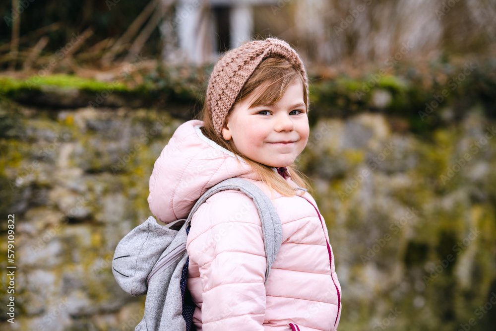 Portrait of happy smiling toddler girl outdoors. Little child with blond hairs looking and smiling at the camera. Happy healthy child enjoy outdoor activity and playing. Portrait of happy smiling toddler girl outdoors. Little child with blond hairs looking and smiling at the camera. Happy healthy child enjoy outdoor activity and playing.