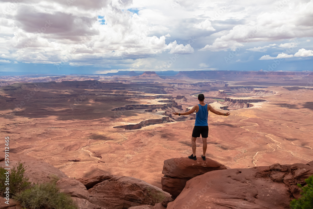 Man with scenic view of Split Mountain Canyon seen from Green River Overlook, Moab, Canyonlands National Park, San Juan County, Utah, USA. Looking at features of The Maze district and White Rim Road