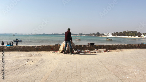 Pescatore che ritira le reti sul lungomare di Hammamet. photo
