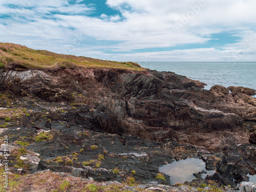 A picturesque rocky coast of the Atlantic Ocean under a blue sky. White clouds in the sky. Seaside landscape. Beautiful nature of northern Europe. © Oleksii
