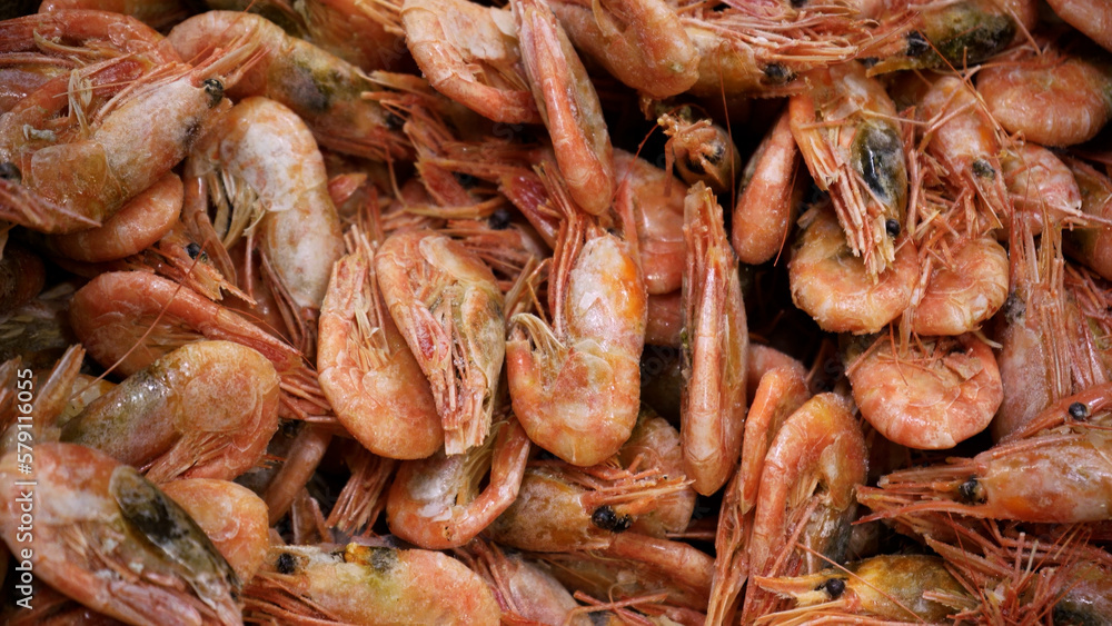 Pink fresh frozen shrimps with ice in a supermarket or fish shop. Uncooked seafood close up background. Fresh frozen prawns, delicacies, sea food concept, close up.