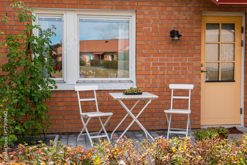 Sweden, Knislinge – September 4, 2022: Chairs and table for relaxing outdoors on the terrace, veranda. Comfort relaxing zone. Recreational area. Cozy and comfortable atmosphere. Sunny day. Private hou photo